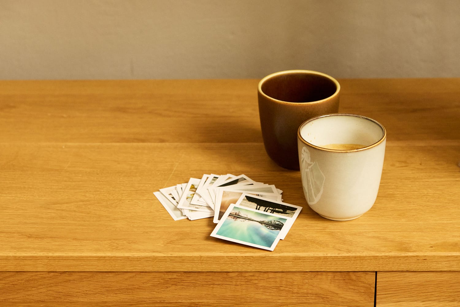 Zwei Kaffeetassen mit Polaroid-Fotos auf Holztisch, Life Coaching.
